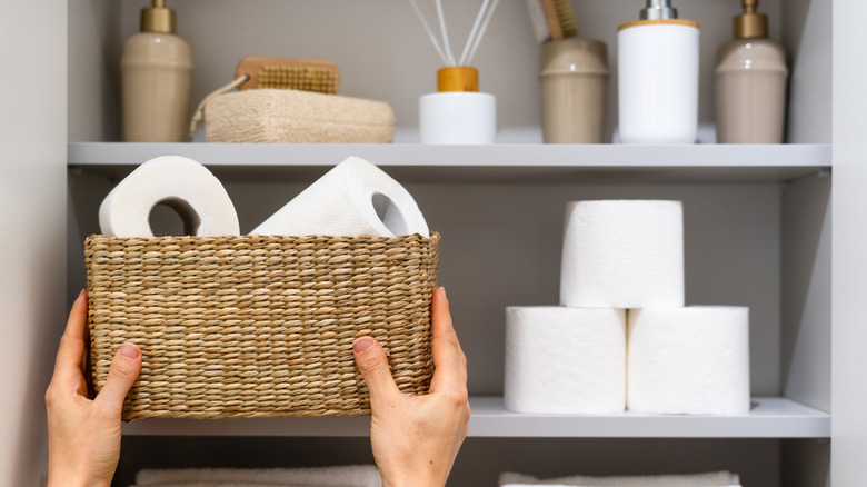 Person grabbing a basket of toilet paper from a shelf