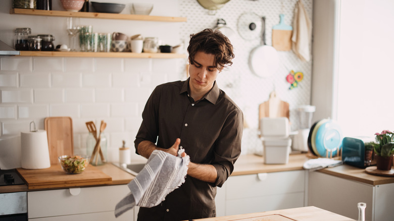 A man uses a gray tea towel to dry his hands