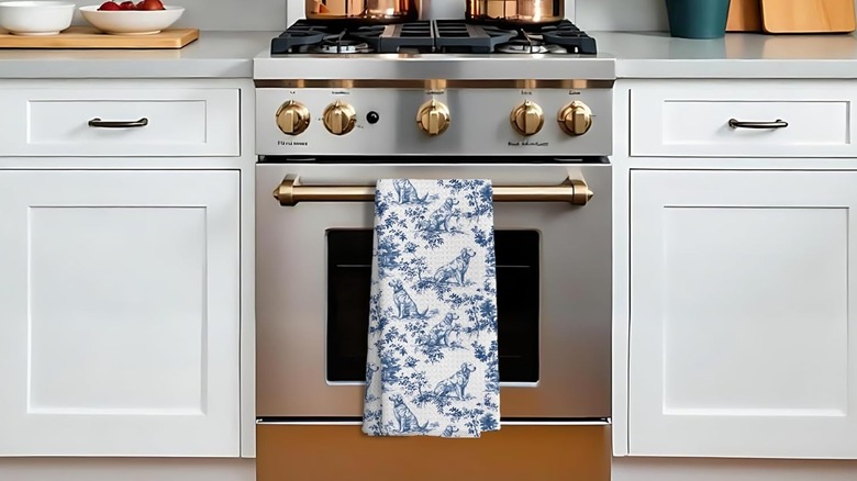 A towel with a vintage-style golden retriever pattern hangs from an oven door.
