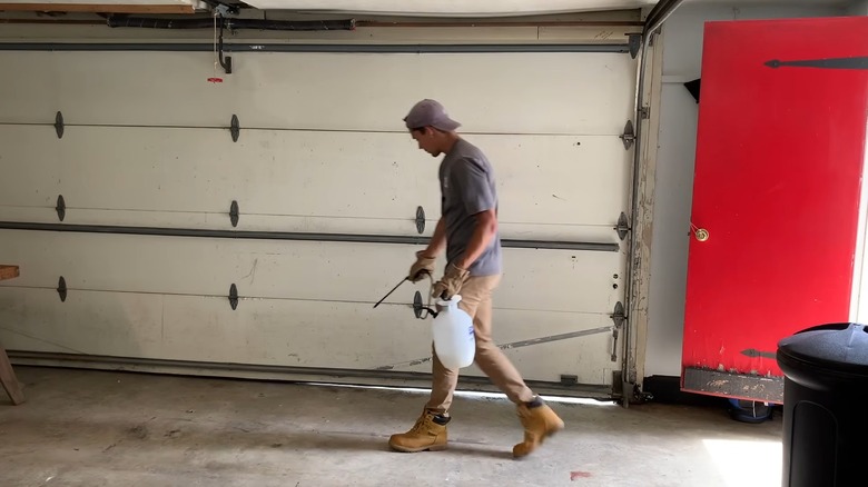 Man spraying insecticidal spray inside a garage