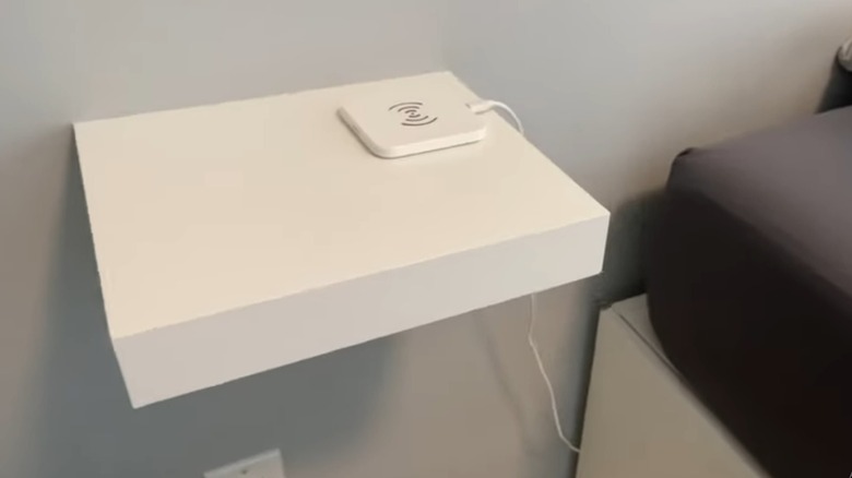 White floating shelf with a phone charger on top