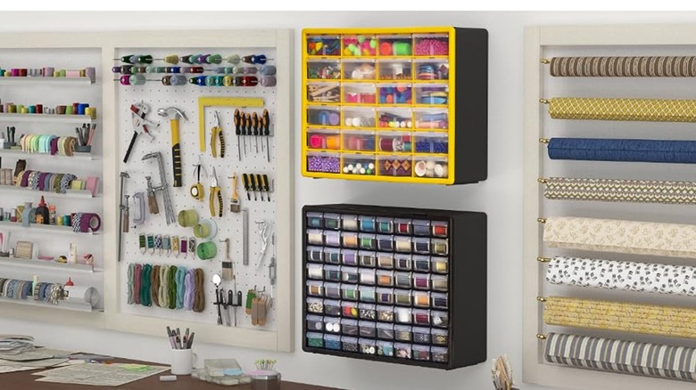 Two plastic storage drawer cabinets hanging from a wall beside tools