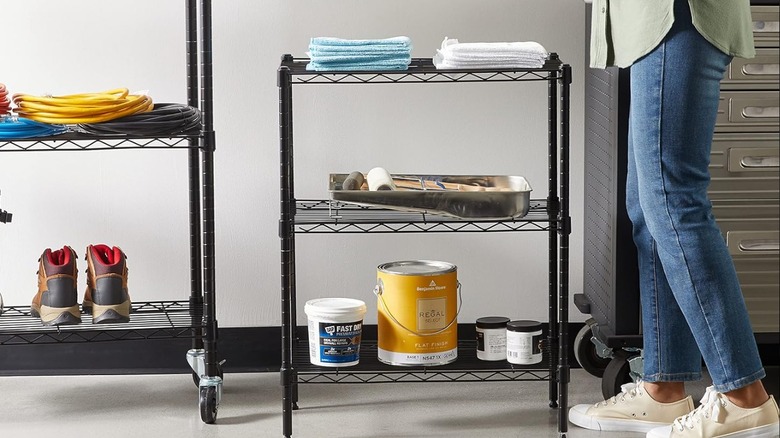 Woman folding a rag and standing beside two heavy-duty storage shelves