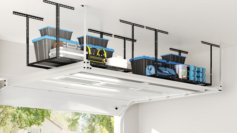 An overhead rack holding storage bins with a car parked in the garage