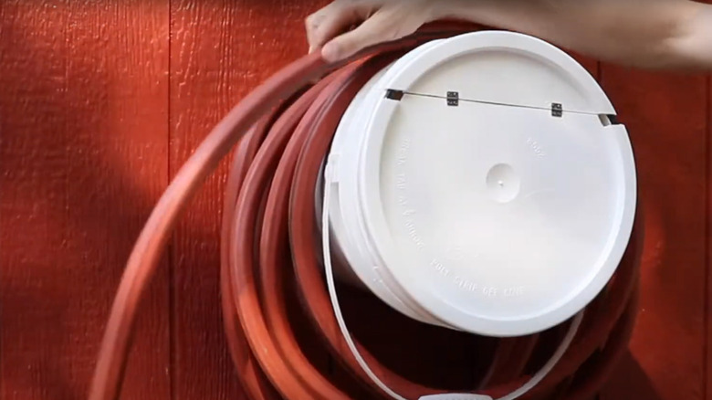 A commercially available hose bucket with hinged lid