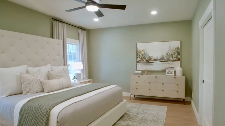 A bathroom with a large double vanity, white walls, and sage green/gray cabinets