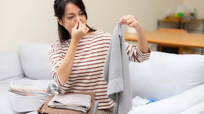 Woman pinching her nose while holding a gray towel