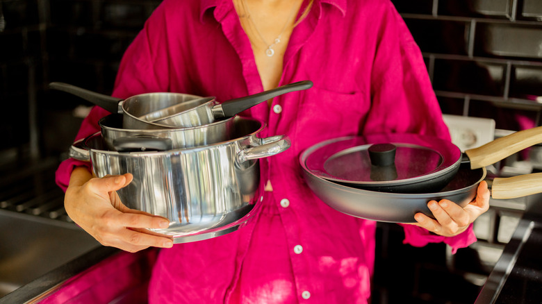 Woman holding pots and pans in both hands