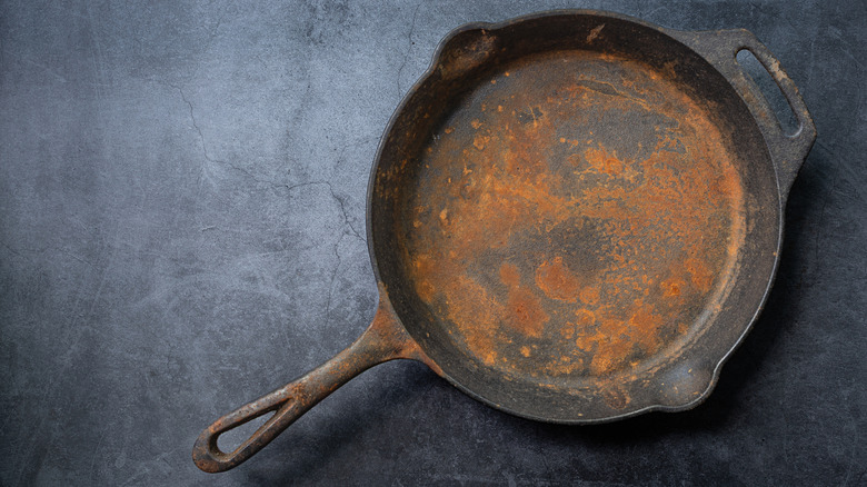 A rusty cast iron pan placed on gray surface