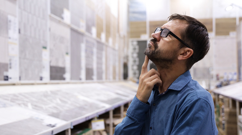 A man wearing a blue shirt choosing tiles in a store