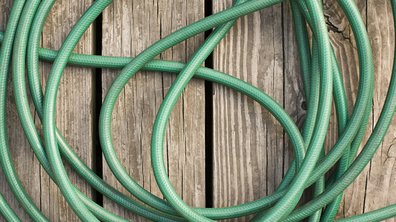 tangled green garden hose on deck floor