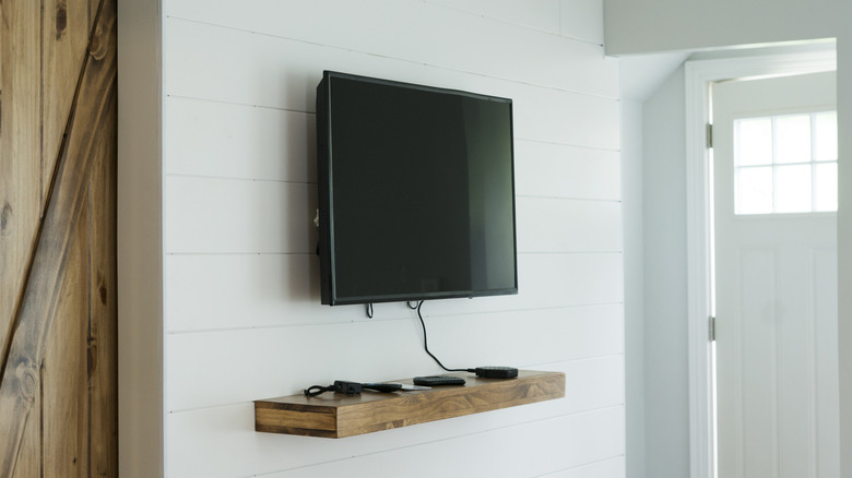 Wall-mounted TV on white all with power cord hanging down