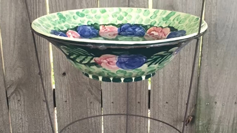 Decorative bowl sitting in a tomato cage to create a birdbath