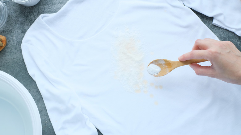 Applying white powder to yellow stain on white shirt
