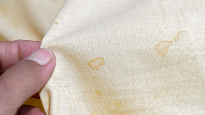 Hand examining yellow-stained linen fabric