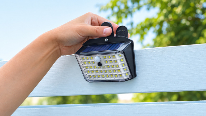 Close of up a hand clipping a solar light onto a rail.