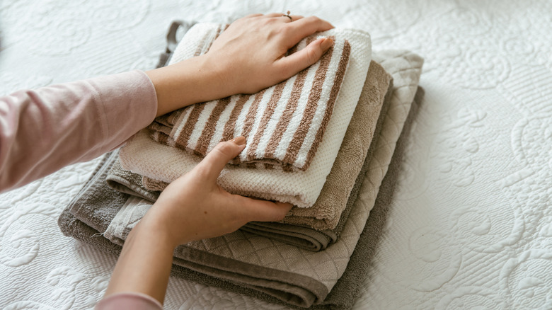 A person folding a stack of towels