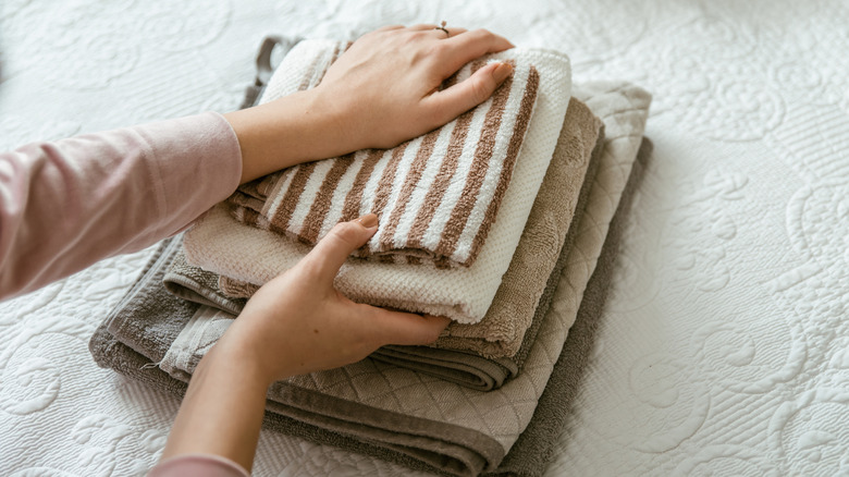 Woman folding towels on a white bed