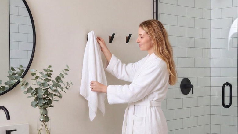 Woman placing white towel on Homeforia Coat Hook in bathroom