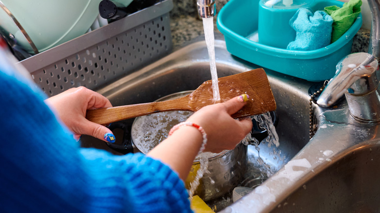 Woman washing spatula and dishes