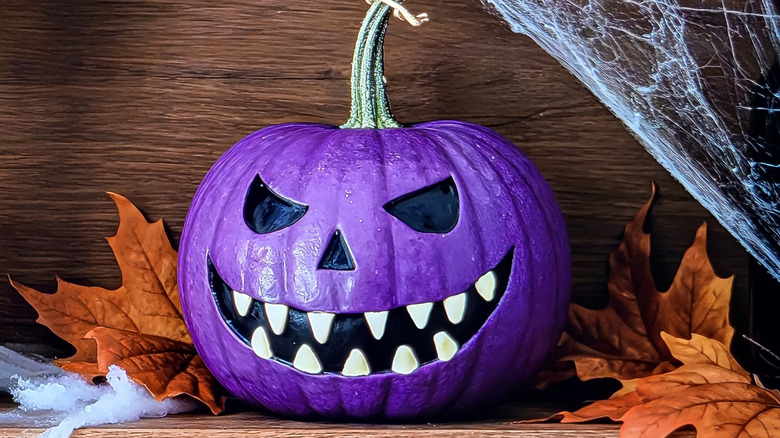 pumpkin painted as a purple Jack-o'-lantern
