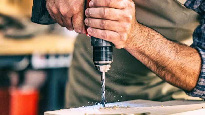 Shop wprker drilling through hardwood with hand drill