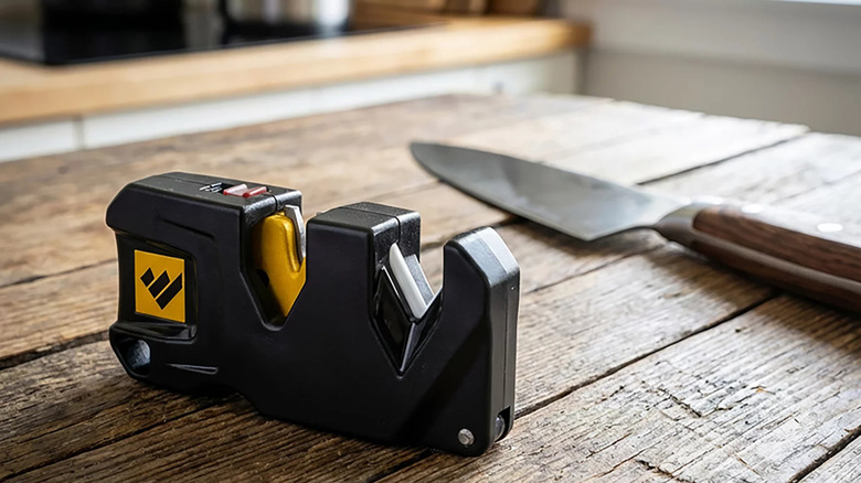 The Work Sharp Pivot Plus Knife Sharpener on a kitchen table with a knife in the background.