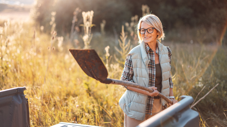 A woman holds a shovel against a sunny background