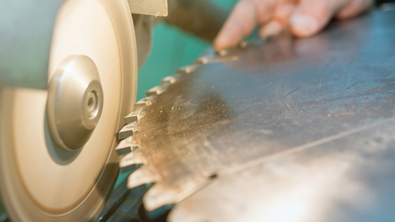 A saw blade being sharpened with a bench grinder