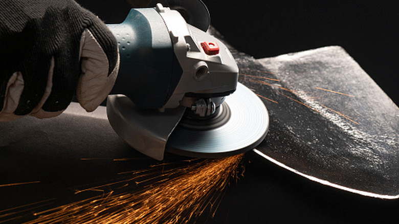 Angle grinder sharpening a shovel blade with sparks flying down