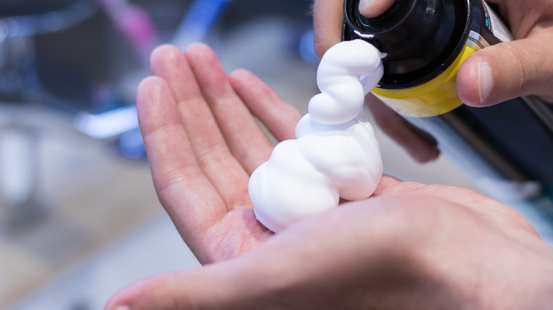 Person squeezing out shaving cream from a can onto their hands