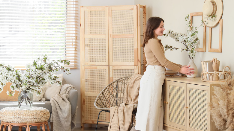 Woman in whimsical floral living room with wicker accents