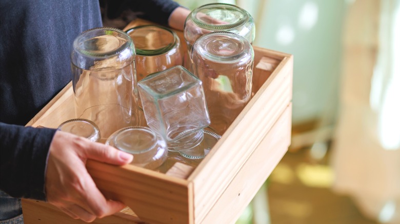 Person holding wood box full of empty glass jars