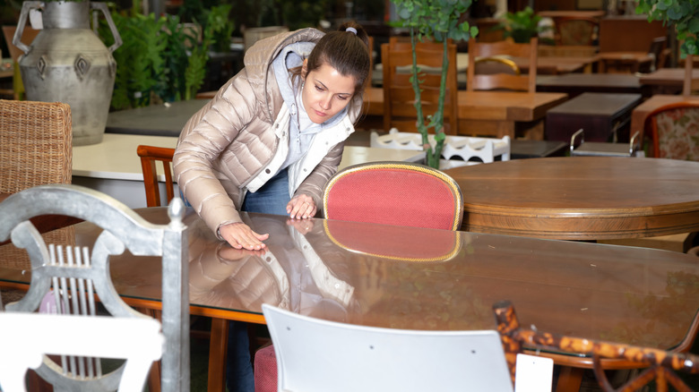 woman looking at wood table in thrift store