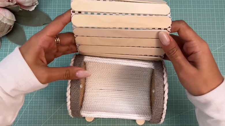 Creator attaching the lid portion made from craft sticks to the main container
