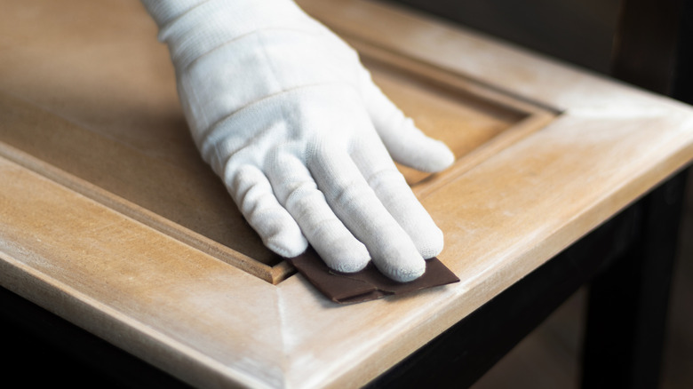 Person sanding a cabinet door