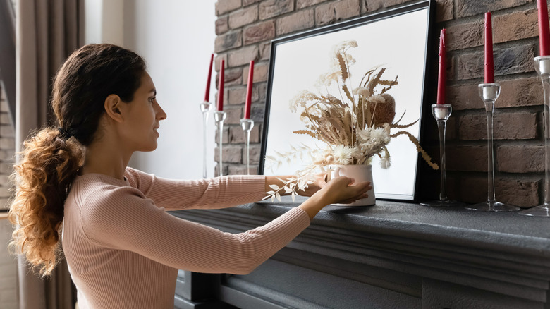 Woman arranging decorations on a fireplace mantel