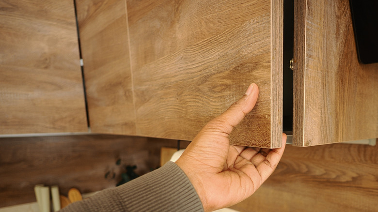 Person opening wood kitchen cabinet door