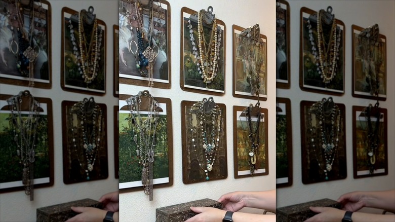 Clipboards hung on wall with art attached, and jewelry hanging from them