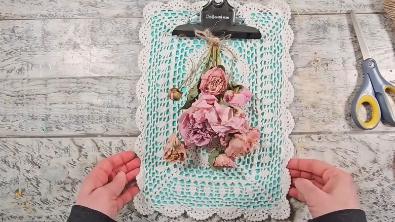 Woman crafting unique rustic floral decor with repurposed clipboard and doily