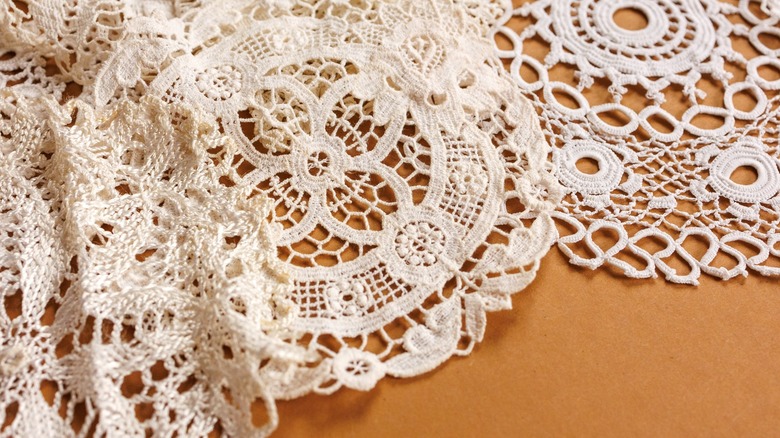 A pile of white, circular crochet doilies on a table