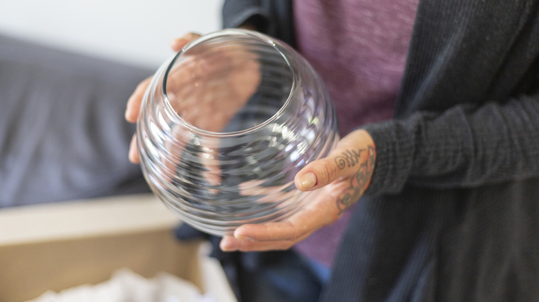 A person holding a glass vase