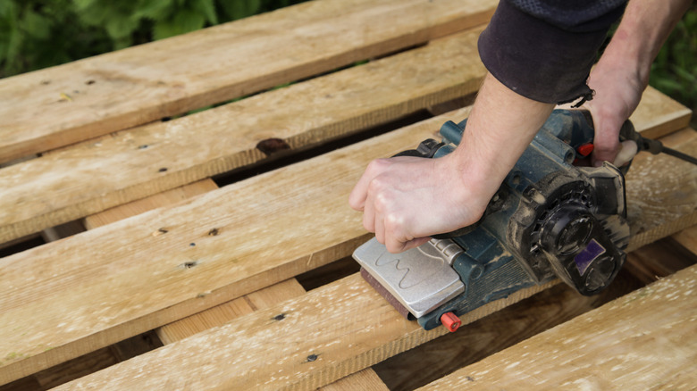 Person sanding a wood pallet
