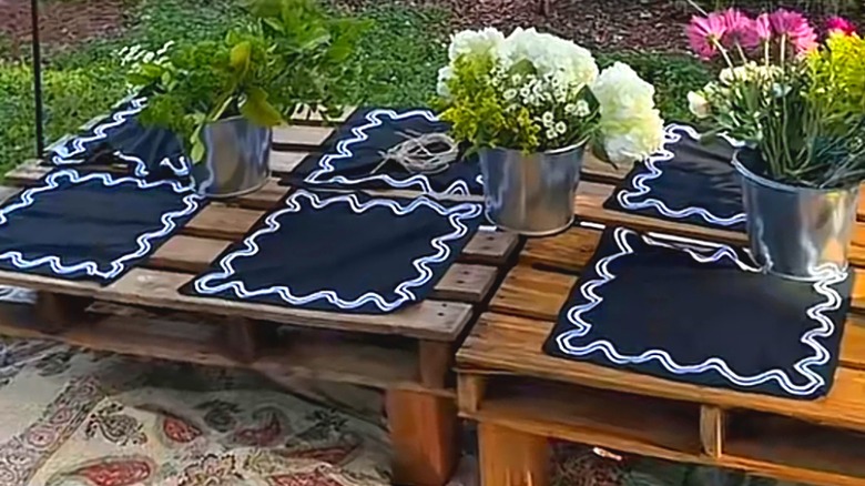 Outdoor picnic table with repurposed wood pallets and decorated with flowers and placemats