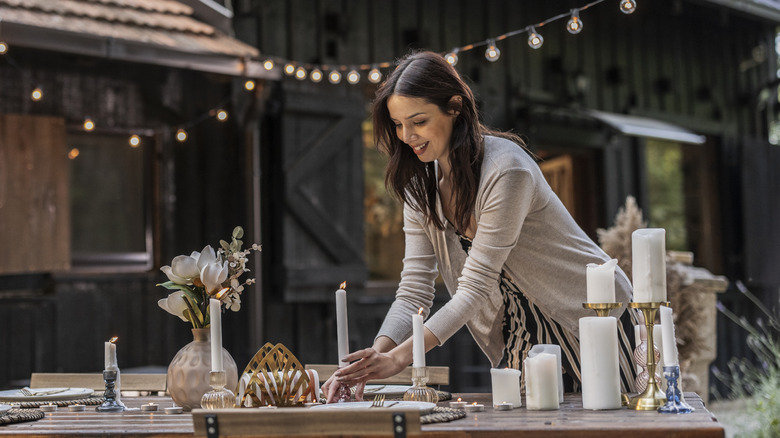Person setting a table outdoors in a garden.