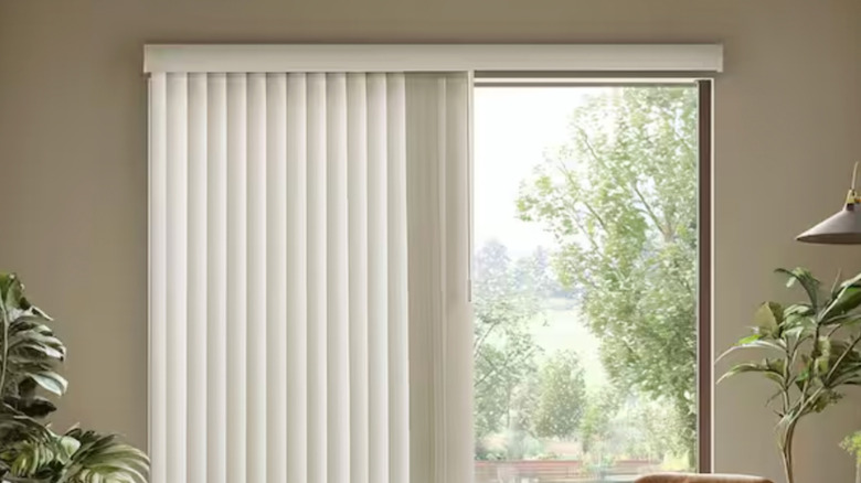 A living room with sheer vertical blinds covering a sliding door