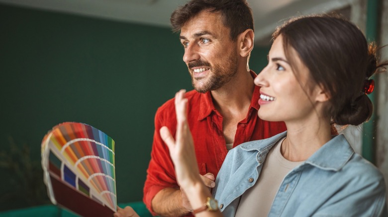 Smiling couple considering paint color swatches in their living room