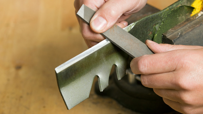 a person sharpening a lawn mower blade