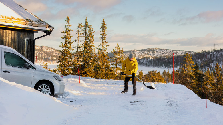 Man with a shovel moving heavy snow away from a driveway