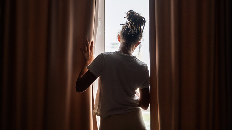 A woman standing in front of a window with curtains
